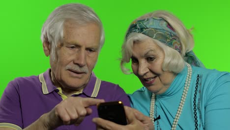 una pareja de ancianos maduros y abuelos disfrutan de las compras en línea en el teléfono móvil.