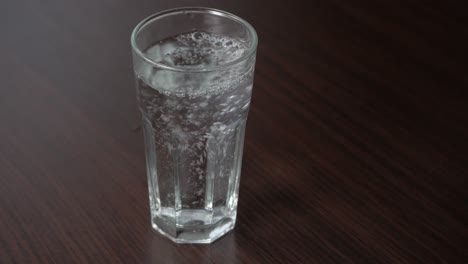 Verter-Agua-Sin-Gas-En-Un-Vaso-Alto-Sobre-Una-Mesa-De-Madera