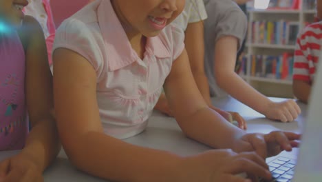 Animation-of-glowing-light-over-diverse-school-children-using-laptop-in-classroom