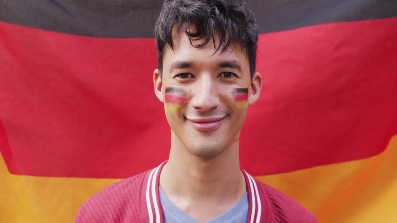 Portrait of happy biracial man with flag of germany in background and on cheek