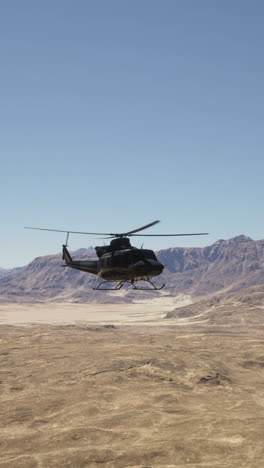 black helicopter flying over a desert landscape