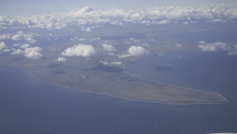 drifting white clouds floating above pristine desert island, revealing turquoise waters, white sandy coastline, and untouched tropical landscape from aerial perspective