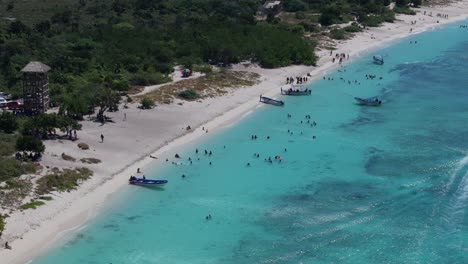 Aerial-high-angle-overview-of-tourists-swimming-on-sandy-shores-of-Bahia-de-Las-Aguilas-beach