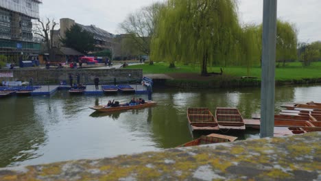 tracking pan follows tour guide and tourists float down river boat in england