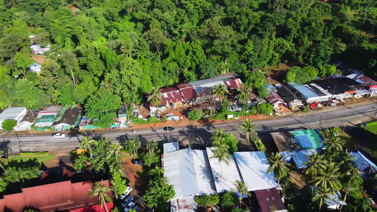 antena: el dron viaja de izquierda a derecha por encima de la carretera rural en el pueblo tropical en la isla de koh chang en tailandia, asia