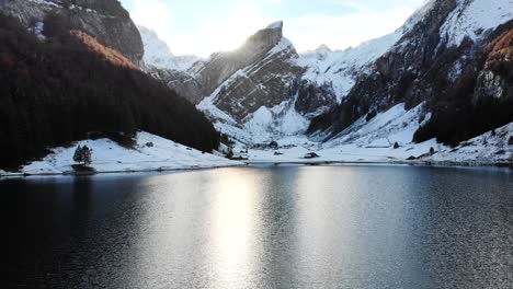 Luftüberführung-über-Dem-Wasser-Des-Seealpsees-In-Appenzell,-Schweiz-Im-Winter-In-Richtung-Der-Klippen-Von-Alpstein-Mit-Schnee---4k