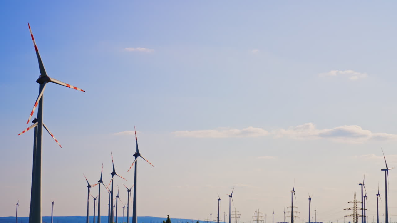 Turbines create clean energy. Large wind turbines tower over lush green fields under a clear blue sky, showcasing renewable energy production