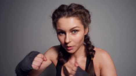 close up view of a young woman training with her hands wrapped in boxing tapes and looking in the camera. boxing in slow motion