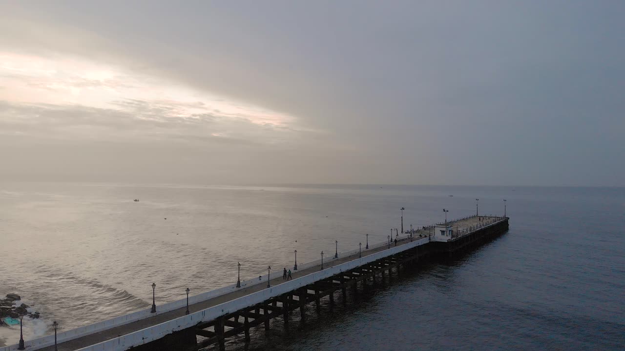 드론, 폰디체리, 인도와 함께 바위 해변 근처에 덮힌 몬순 구름과 함께 일출에 선적항 부두의 4k 공중 크레인 샷