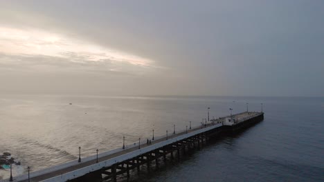 4k aerial crane shot of a shipping port pier on a sunrise with monsoon clouds covered near rock beach shot with a drone, pondicherry, india