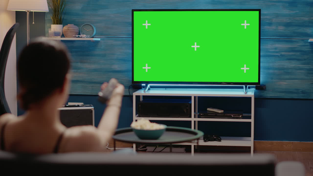Caucasian woman looking at tv with green screen