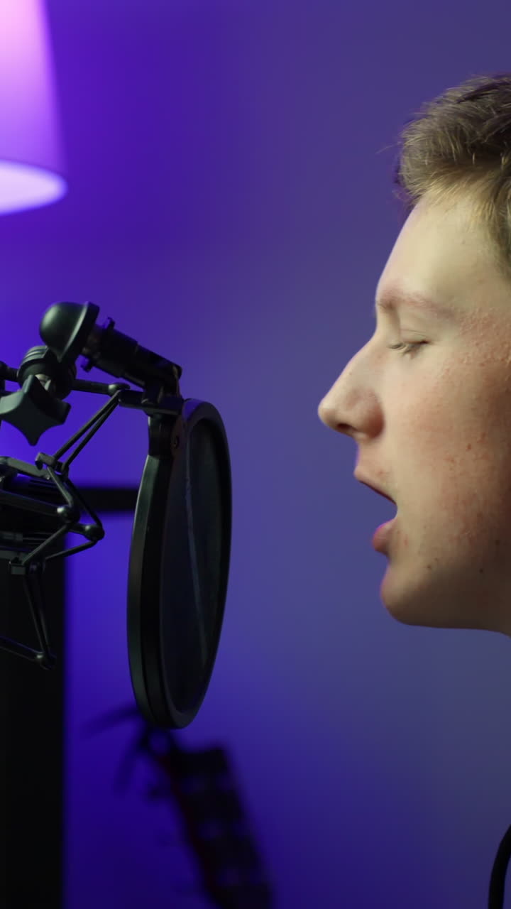 Musikproducer synger i studiets mikrofon, fokuseret hjemmeoptagelsessession, vertikal