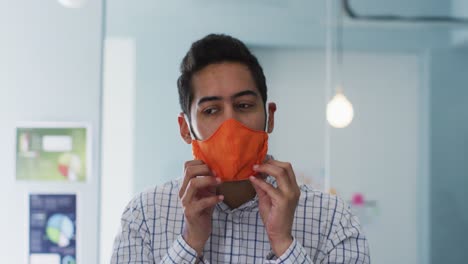 portrait of middle eastern man adjusting his face mask at modern office