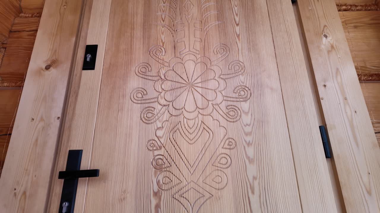 Primer plano de una entrada de madera ornamentada con tallas detalladas estilo montañés en una cabaña rústica de madera