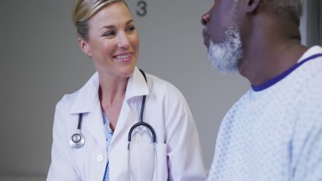 caucasian female doctor talking to african american senior male patient at hospital