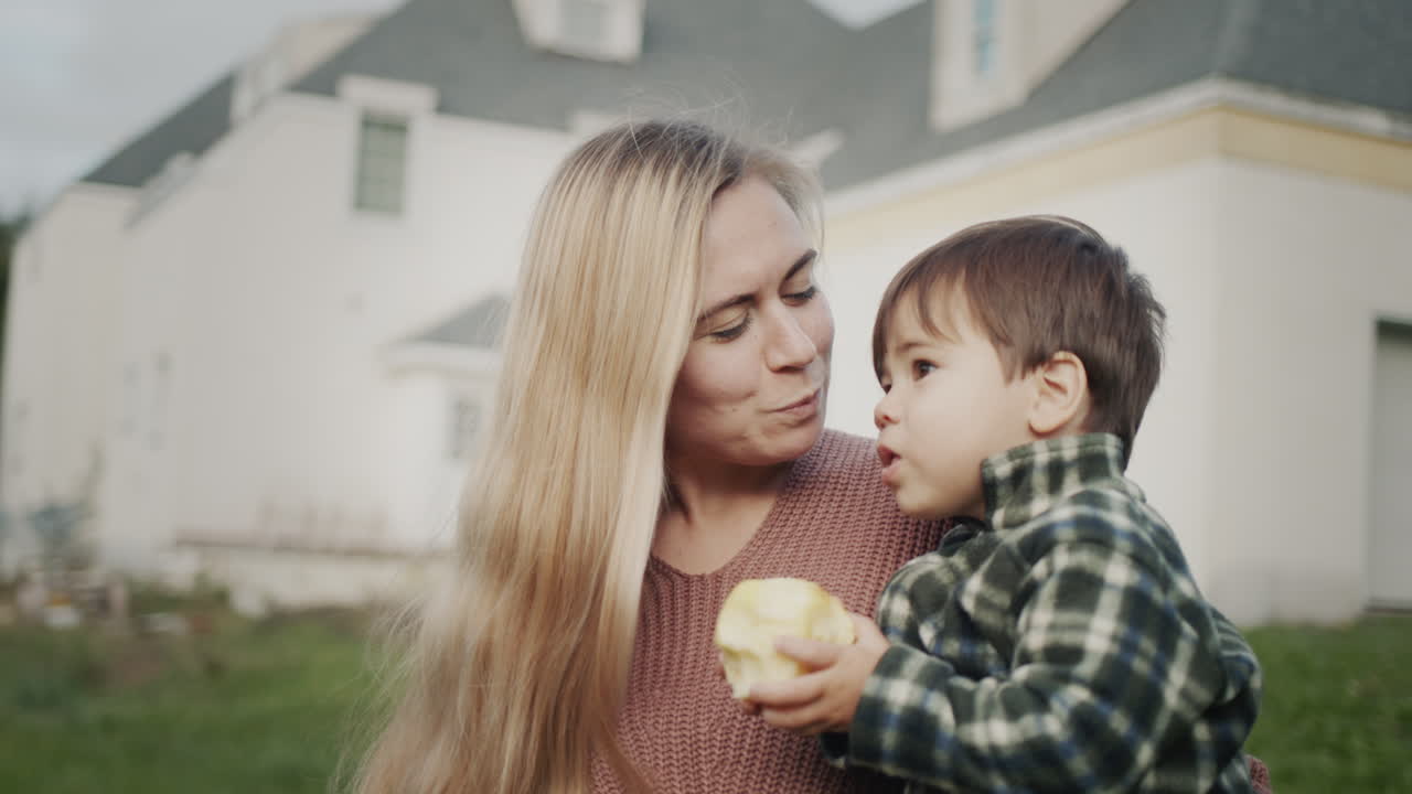 retrato de una madre feliz con un bebé en sus brazos contra el fondo de una casa grande