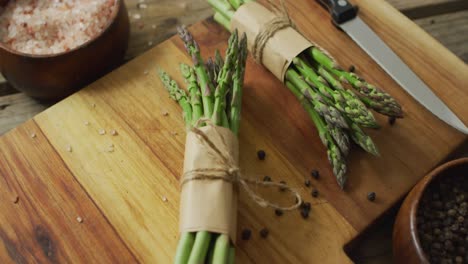 video of two fresh asparagus bundles on wooden chopping board