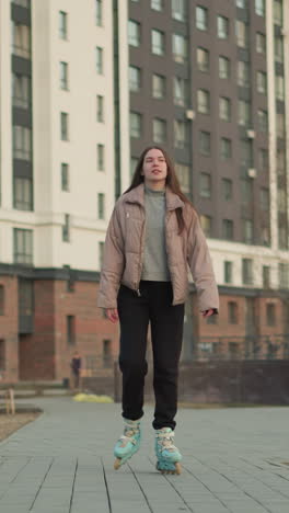 een jonge vrouw in een perzikjacket en zwarte broek die gelukkig rolschaatsen door een modern stedelijk gebied, met haar handen uitgestrekt. op de achtergrond staan hoge woongebouwen, bomen
