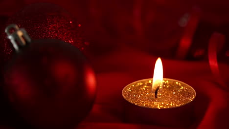 gold glitter candle flickering beside bauble