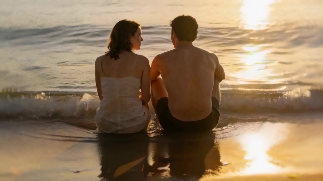 Sitting couple sundress shirtless talking on wet sand ocean at sunset waves lapping sun reflecting