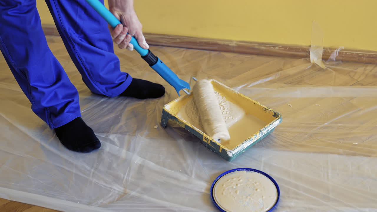 Young worker painting in room. Man painting wall during home decoration with roller brush