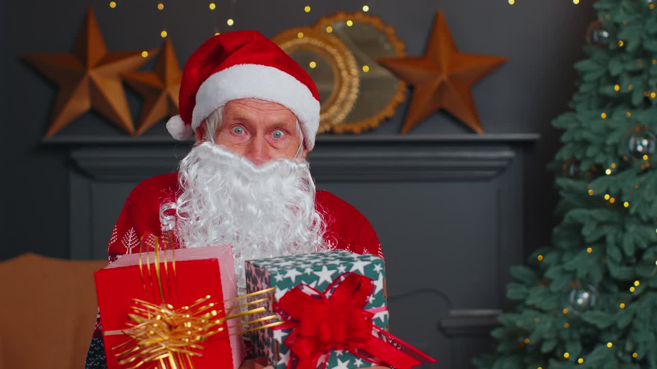 Senior grandfather parodies santa claus presenting christmas gift box holidays celebration at home