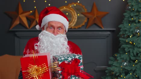 senior grandfather parodies santa claus presenting christmas gift box holidays celebration at home