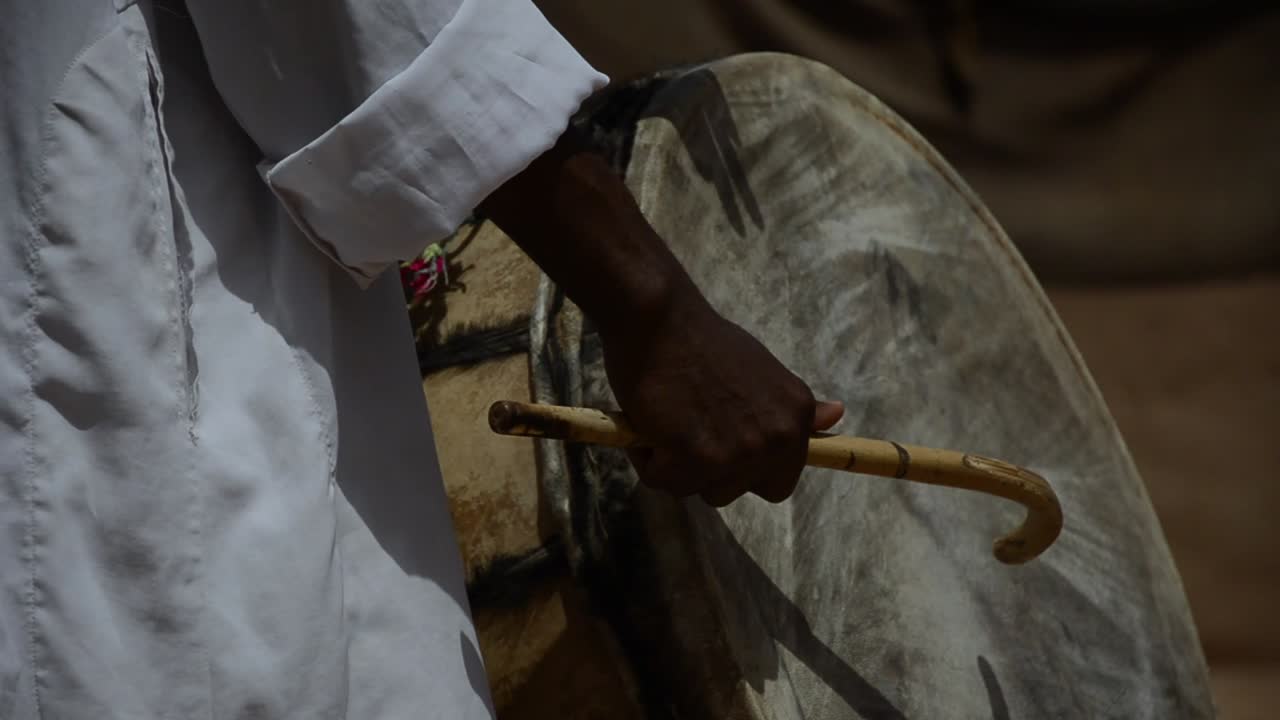 músico bereber tocando el tambor tradicional en el desierto del sahara, marruecos