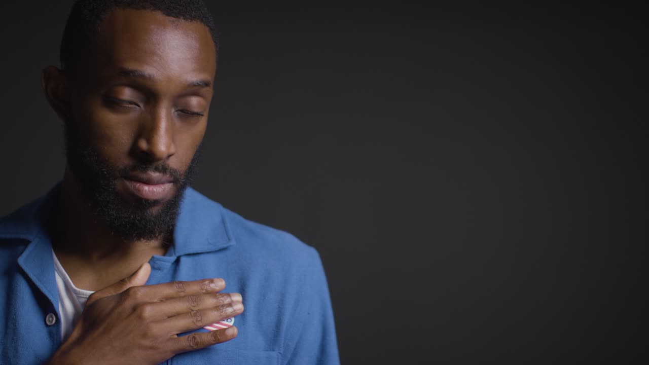 Portrait Of Man Putting I Voted Sticker On Shirt In American Election
