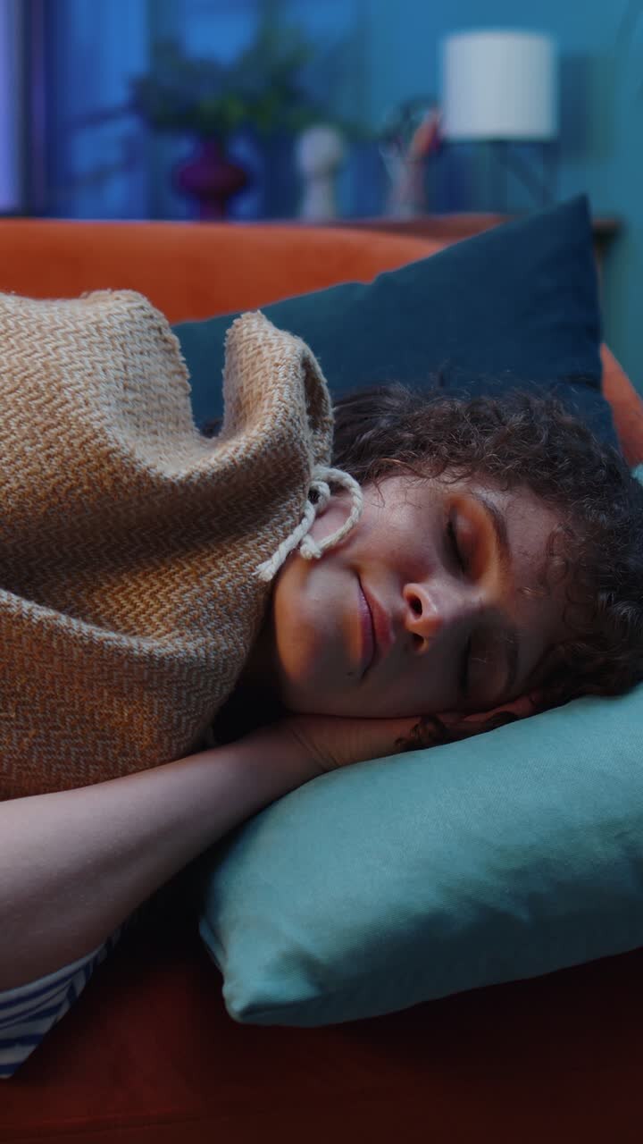Vermoeide brunette jonge vrouw ligt in bed, rust thuis, dut en valt in slaap op de bank.