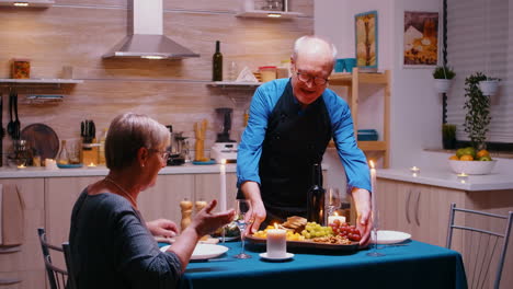 un anciano senior sirviendo la cena a su esposa