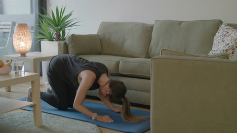 women trembles while trying to do yoga in her cluttered house