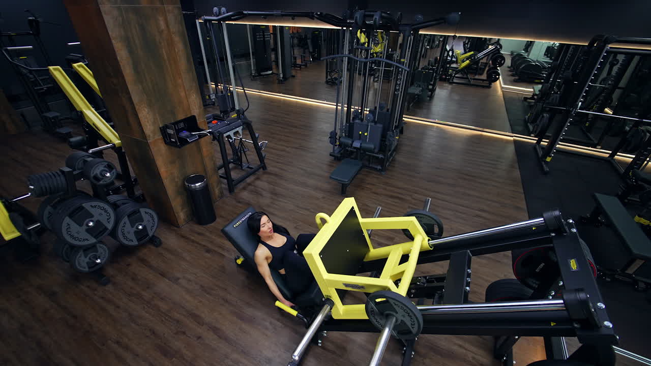 Mujer ejercitándose en prensa de piernas en gimnasio moderno