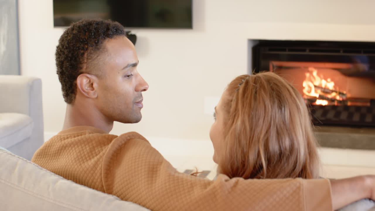 Couple relaxing by cozy fireplace, enjoying warm holiday moments together