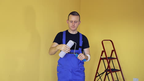 portrait of a handsome man worker with tool for paint. painter holding new paint roller before starting interior decoration. offering professional painting services.