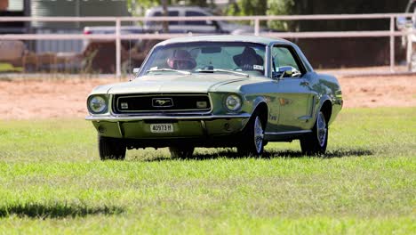 classic muscle car driving across a grassy area