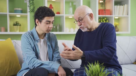 elderly grandfather is arguing with his grandson at home about a topic, senior grandfather is giving an opinion.