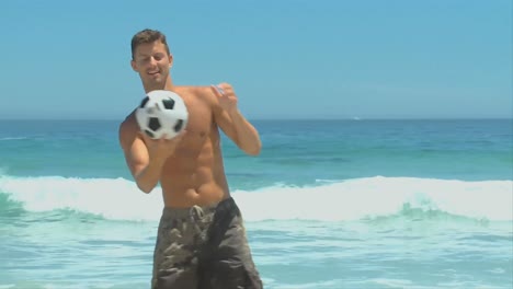 man coming out of the sea to pick up a soccer ball