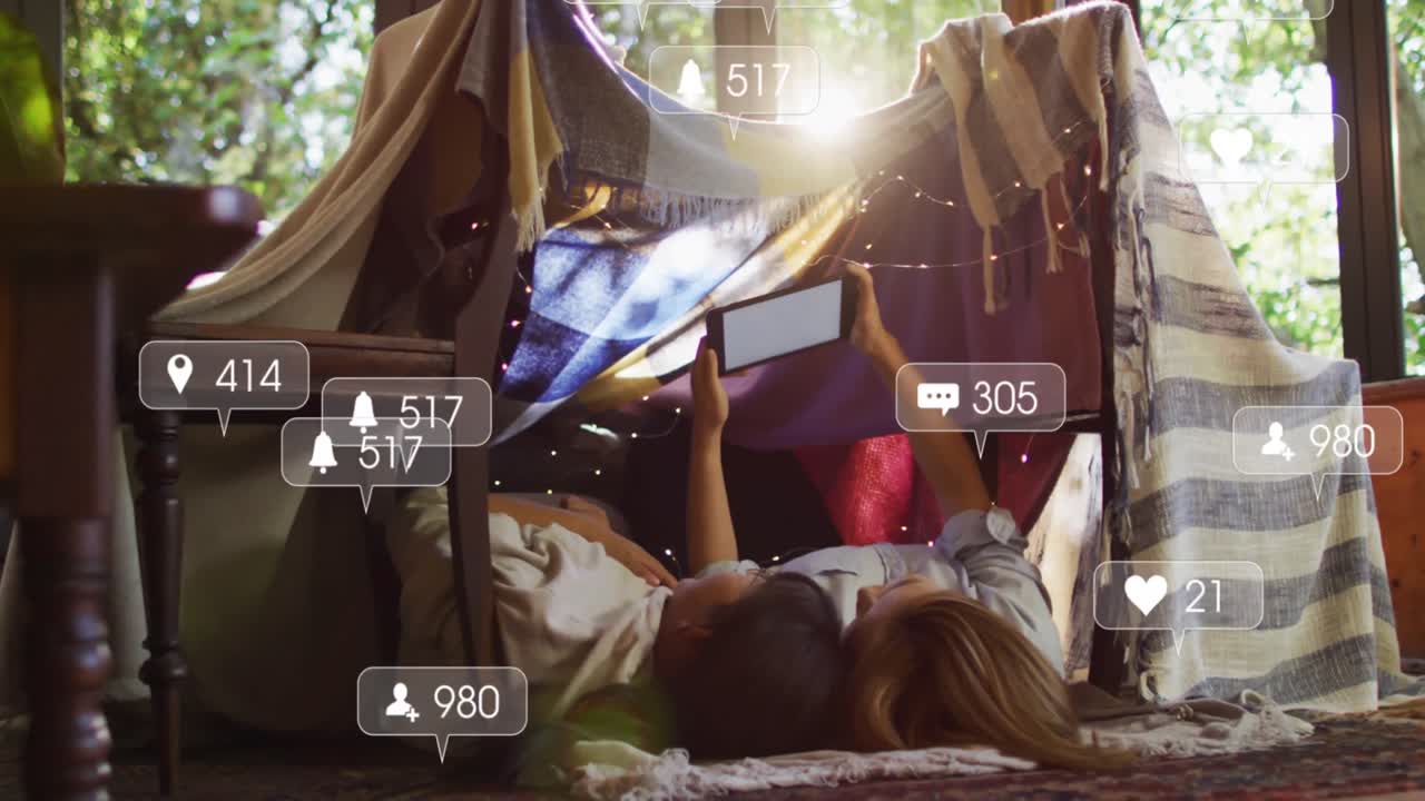 미디어 아이콘 위의 베개 요새에서 태블릿을 사용하는 아시아 어머니와 딸의 애니메이션