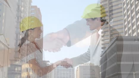 digital composition of silhouette of male and female architects shaking hands against tall buildings