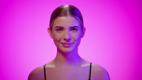 mujer con expresión facial neutral comienza a sonreír, estudio disparado, mirando a la cámara