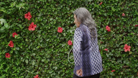 retrato de una anciana india animada bailando juguetona disfrutando escuchando música en auriculares al aire libre fondo del jardín retiro feliz vista trasera