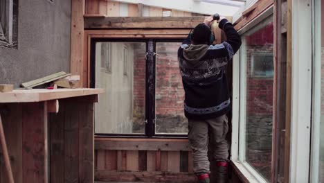 Greenhouse Construction - Man Assembling Wooden Interior By The Window