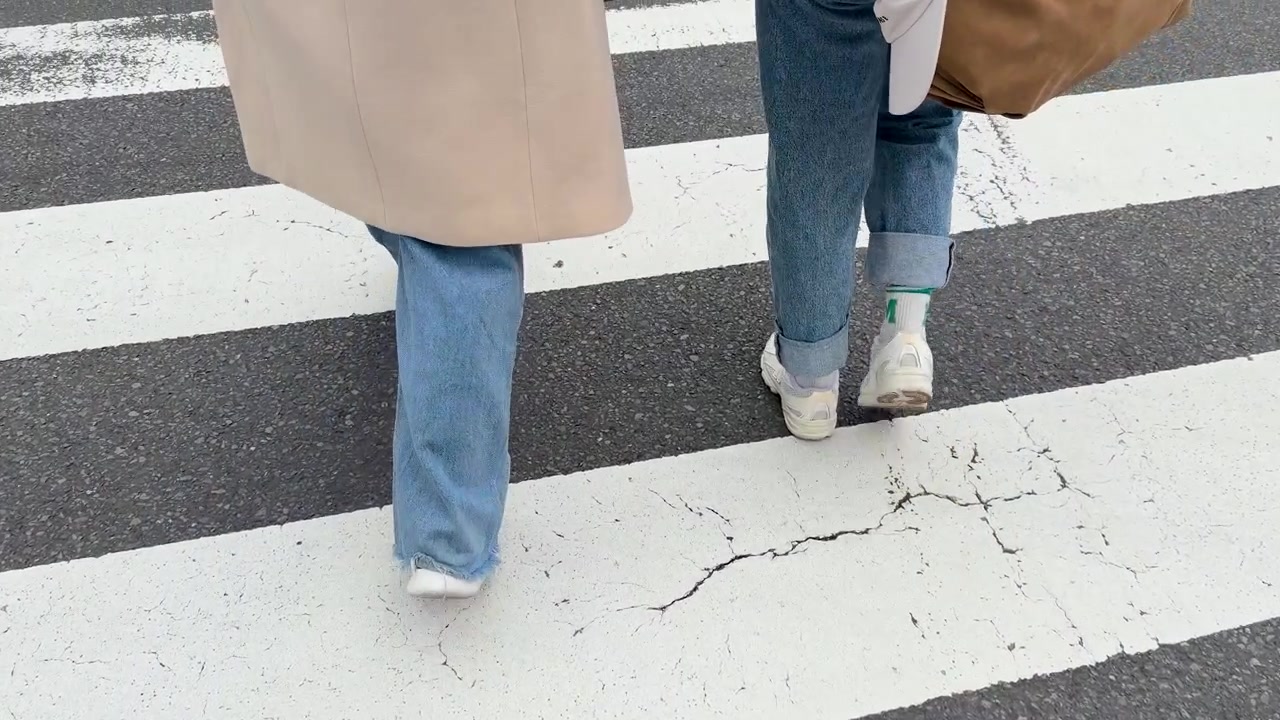 Dua Orang Berjalan Melintasi Penyeberangan Pejalan Kaki
