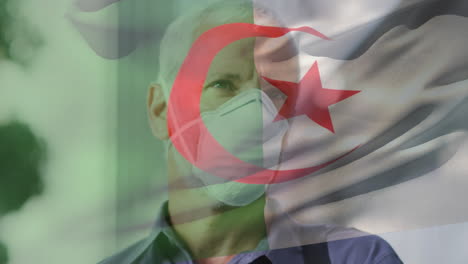 animation of flag of algeria waving over caucasian man wearing face mask in city street