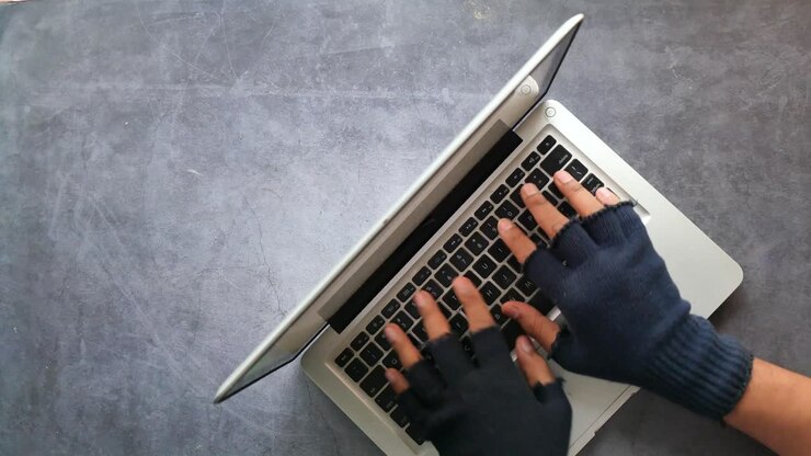 Person Typing on Laptop with Gloves
