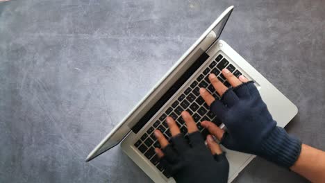 person typing on laptop with gloves