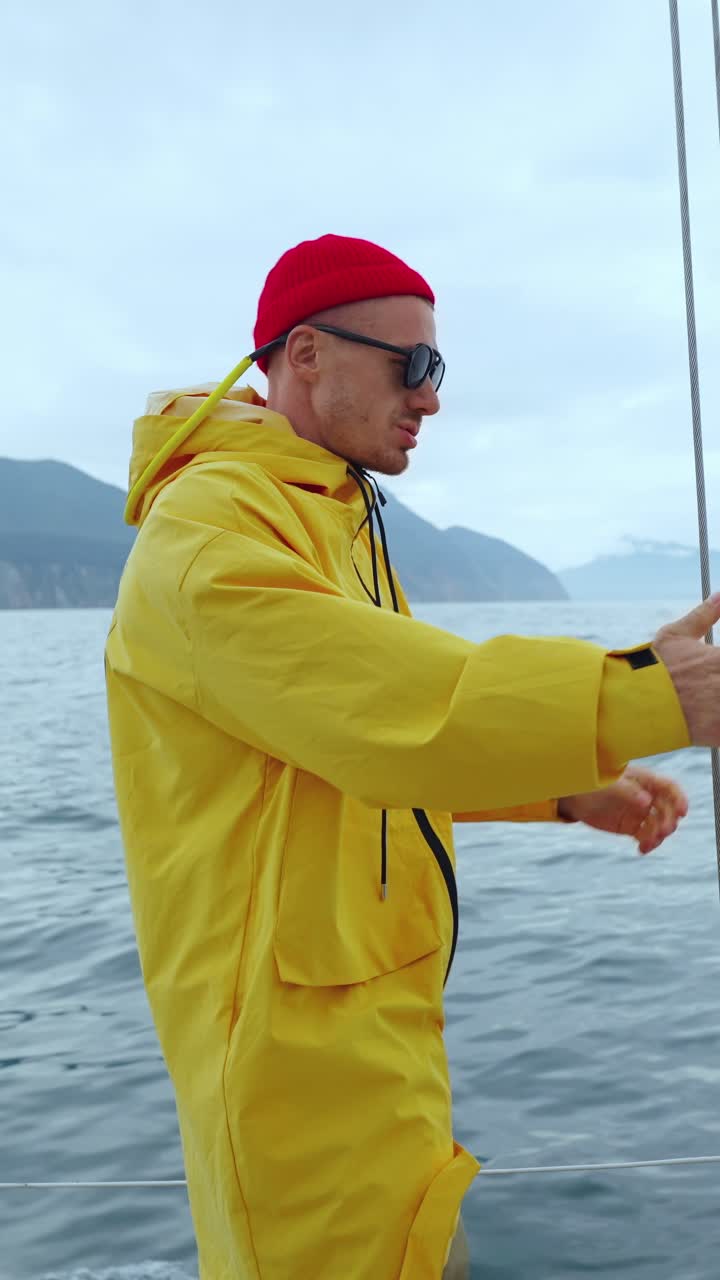 Mand i gul regnjakke og rød hue sejler på havet