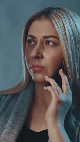 pensive blonde female patient talks on mobile phone with doctor looking at x-ray picture in shady apartment room in evening close view slow motion