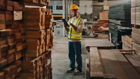 a worker in a warehouse inspecting lumber using a tablet